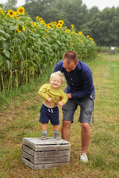 A person and a child standing on a podium in front of a sunflower field
Description automatically generated with low confidence